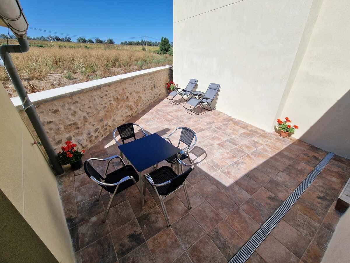 Una familia comiendo al aire libre en una mesa de madera en un patio, con un jardín y un columpio al fondo