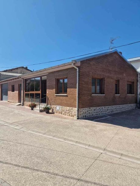 Terraza trasera al atardecer, con mesa de comedor, sillas y parrilla junto a una casa
