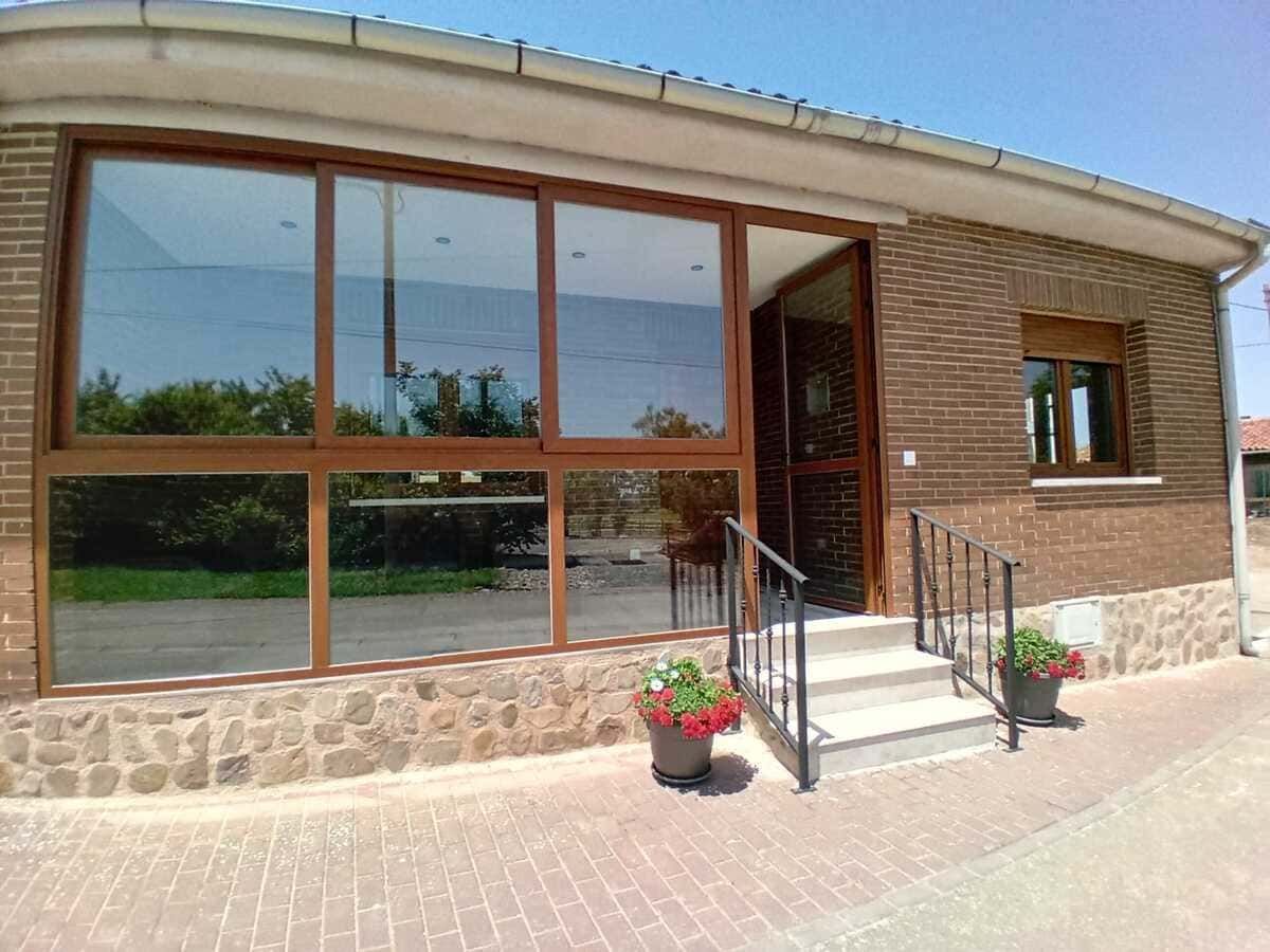 Acogedora cocina y comedor de estilo rústico, con vigas de madera, fregadero de granja y chimenea de piedra encendida