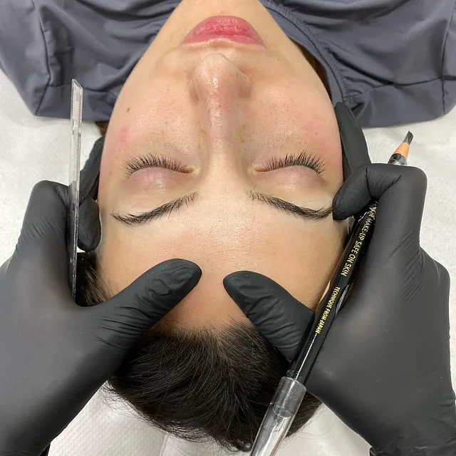 A una mujer que lleva guantes negros le miden las cejas.