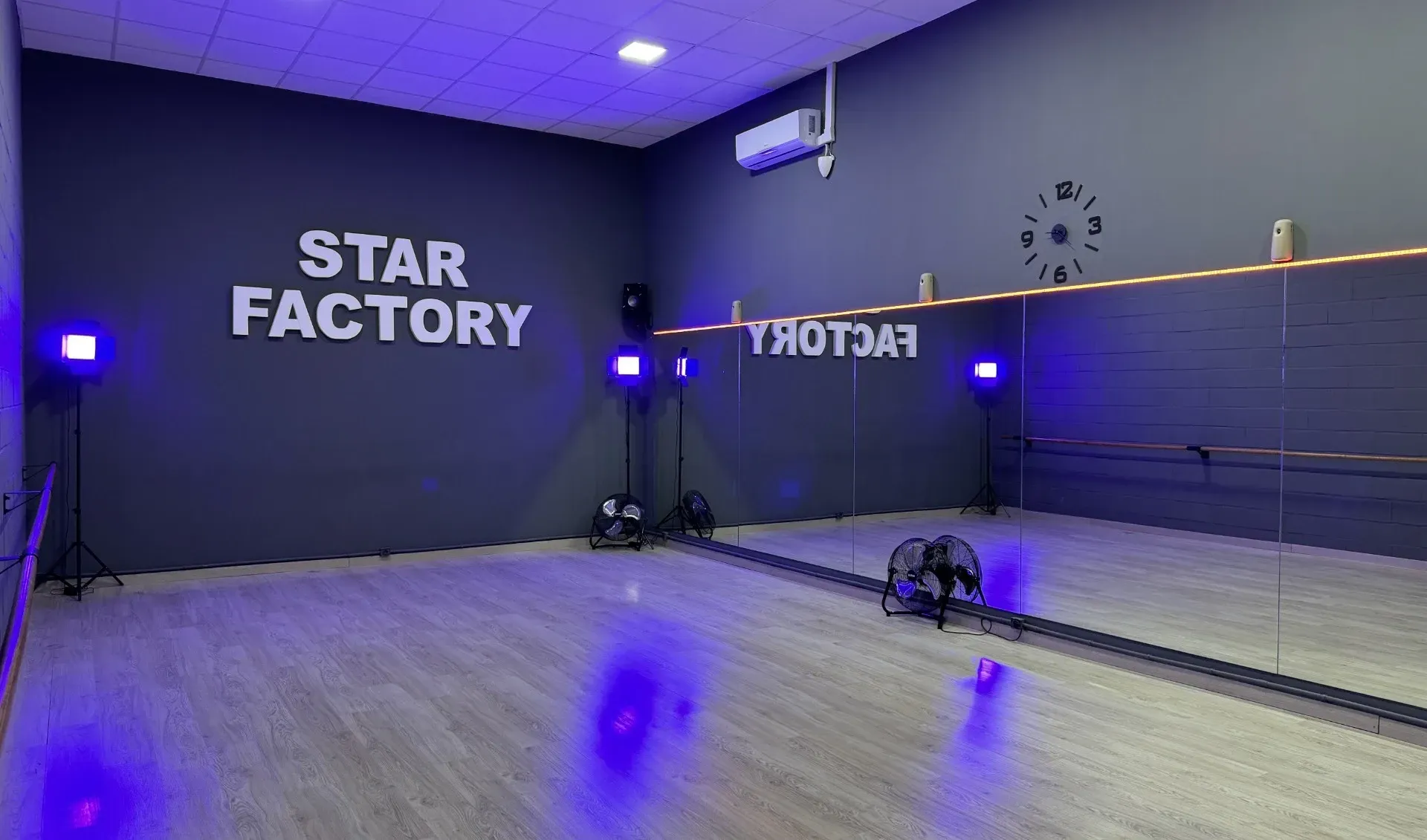 Un estudio de baile con un gran espejo y las palabras Star Factory en la pared.