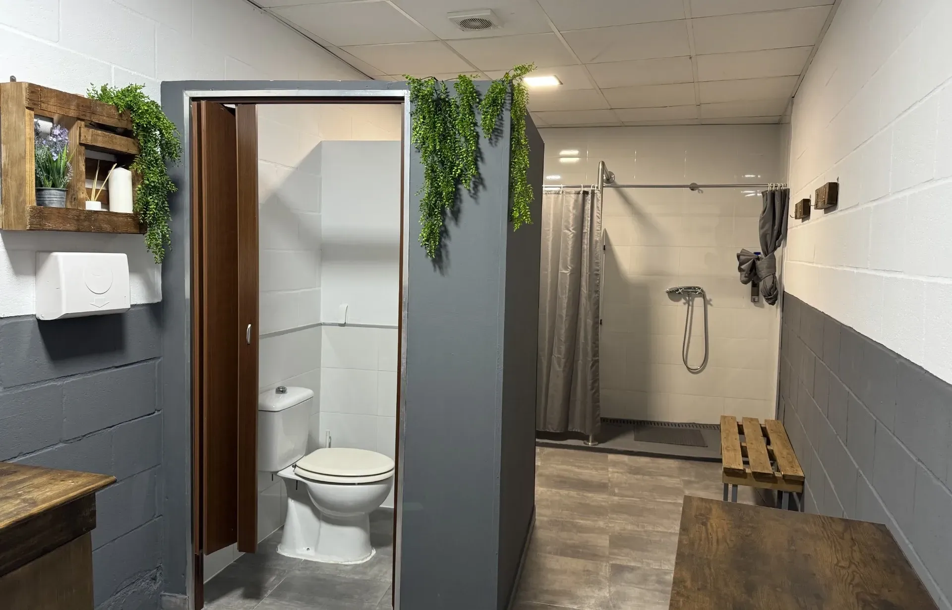 Un baño con inodoro, ducha y bancos.