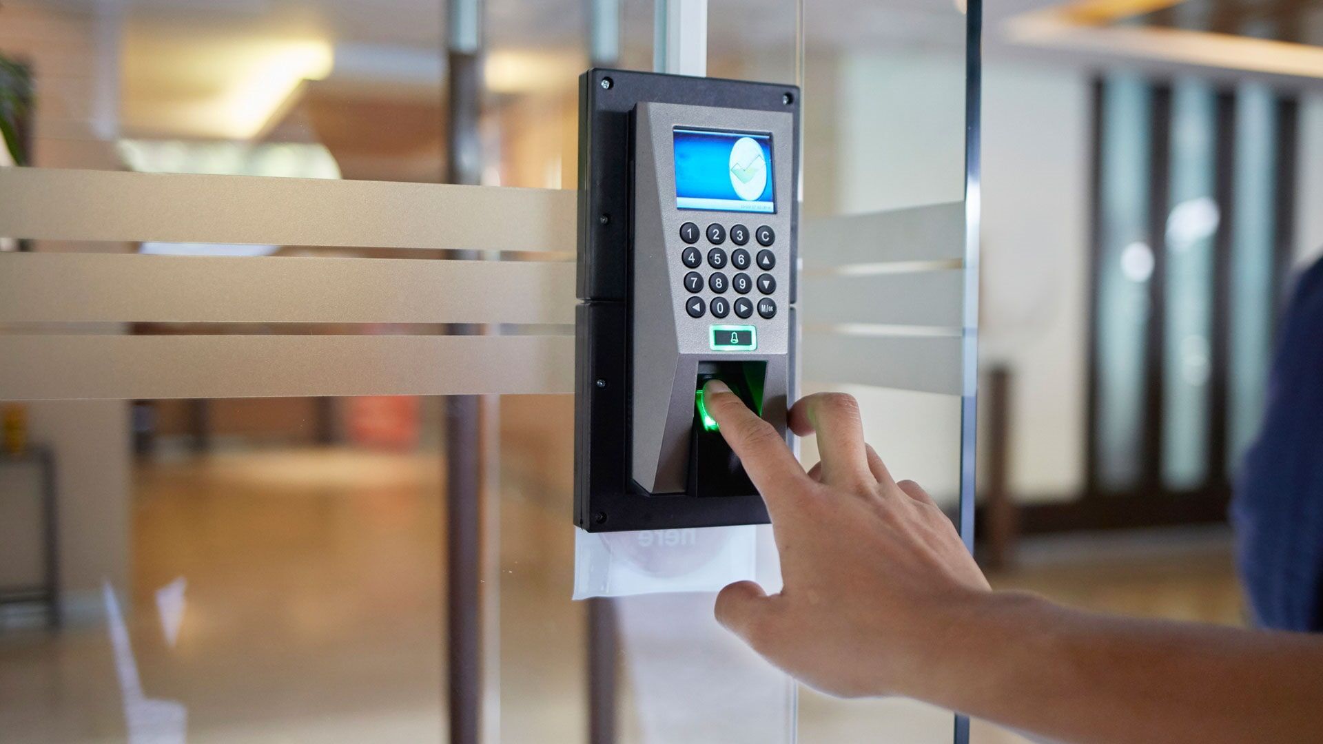 Mão pressionando o dedo em um leitor de impressões digitais em uma porta de vidro