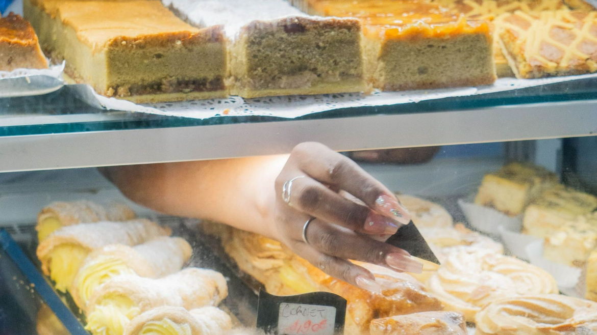 Une vendeuse met un prix sur des gâteaux bien exposés en vitrine