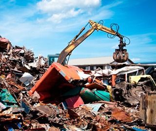 Una gran pila de chatarra está siendo procesada por una grúa.