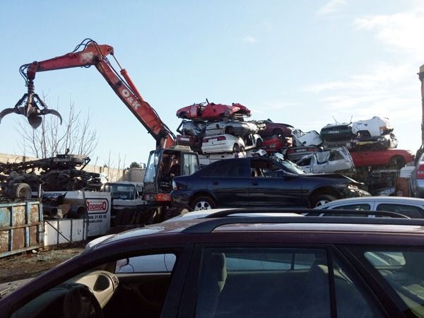 Una grúa está levantando un coche de una pila de coches.