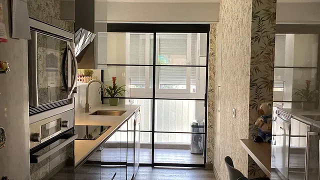 Cocina con diseño moderno, cuenta con puerta corrediza de vidrio y encimeras de madera clara.