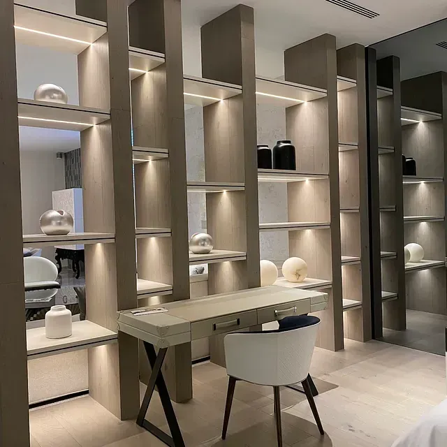 Estanterías empotradas modernas con escritorio y silla; tonos de madera neutros e iluminación cálida.