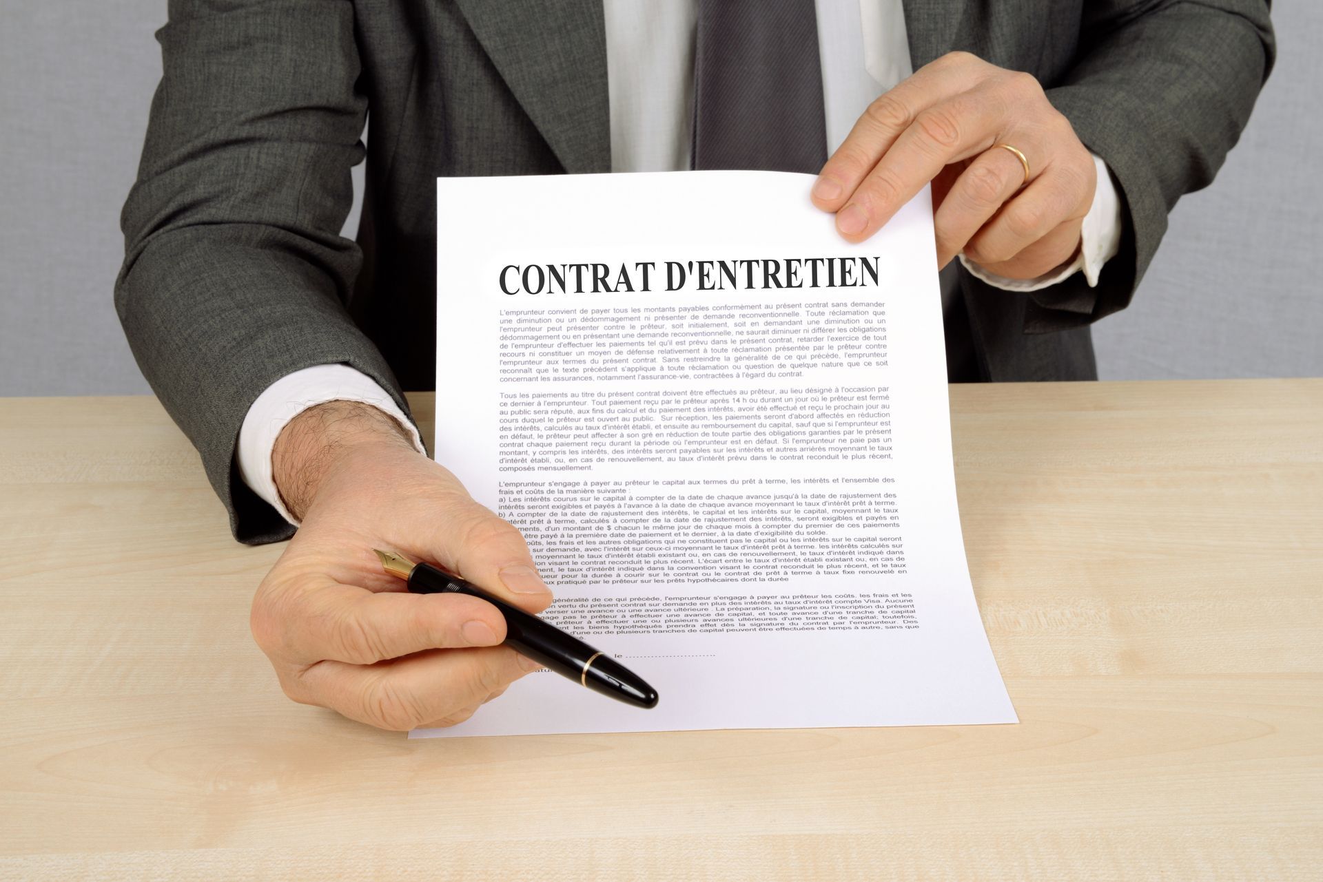 Un professionnel en costume présente un document intitulé Contrat d'entretien.
