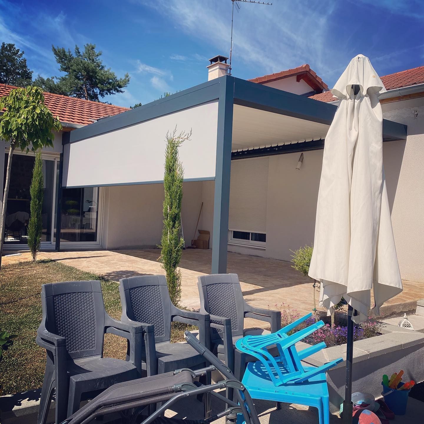 Une pergola grise avec un store enroulé.