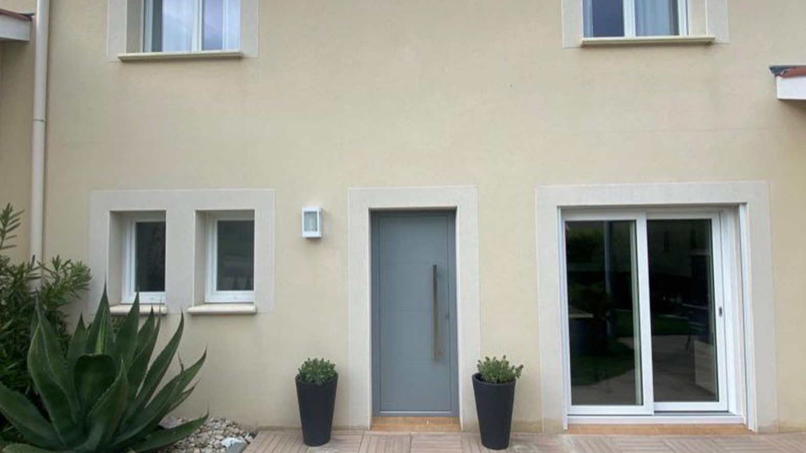 L'extérieur d'une maison beige avec une porte d'entrée grise.