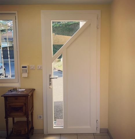Une porte extérieure blanche avec un panneau de verre incliné.