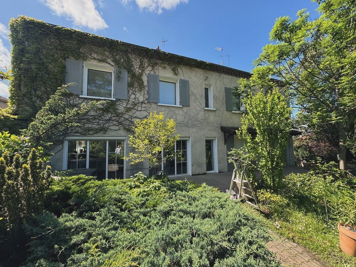 Une maison en pierre de deux étages avec des volets bleus et de grandes fenêtres.