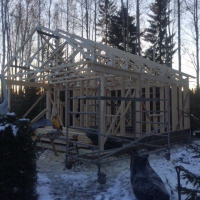 Rakenteilla olevan talon puurunko talvella, etualalla rakennustelineet ja takana puita.
