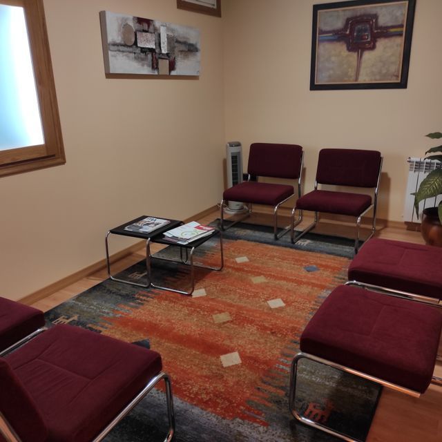 Una sala de espera con sillas rojas y una alfombra.