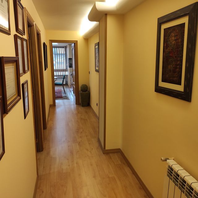 Un pasillo con cuadros en la pared y un radiador.