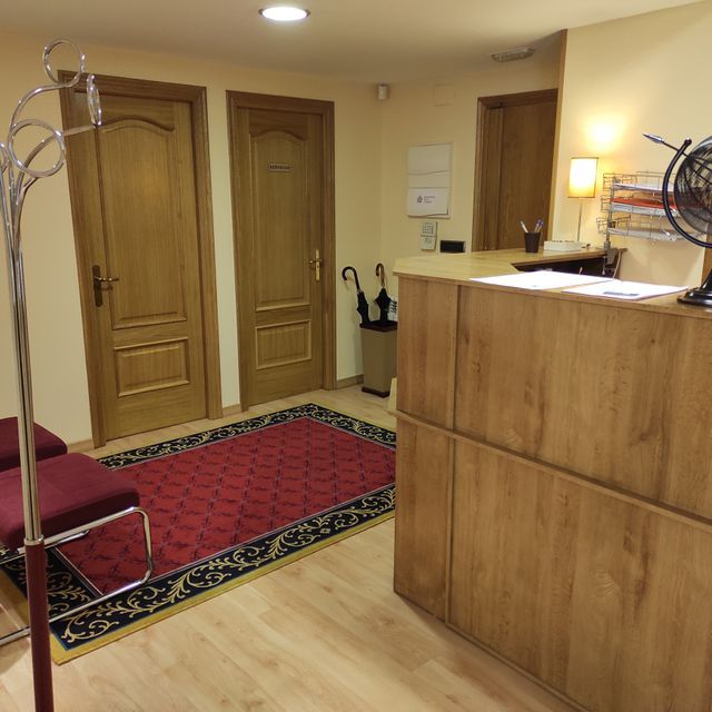 Una sala de espera con un mostrador de madera y una alfombra roja.