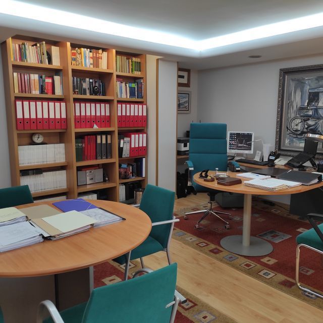 Una habitación con una mesa y sillas con carpetas en los estantes.