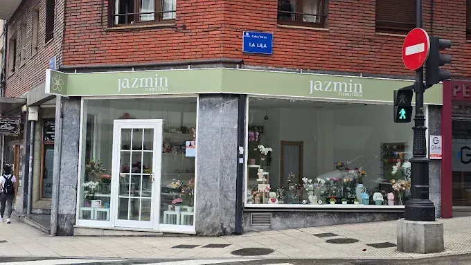 Pareja besándose bajo un velo, sosteniendo un ramo, afuera de un edificio.