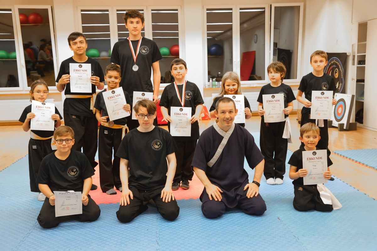 Kampfsportunterricht: Schüler mit Urkunden und Medaillen posieren mit ihrem Lehrer in einem Dojo.