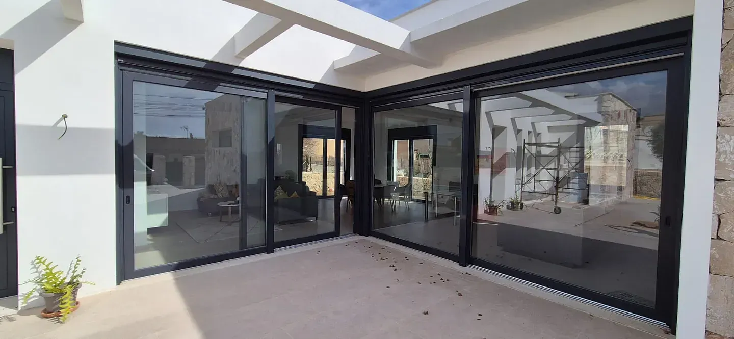 Una casa con muchas ventanas y puertas corredizas de vidrio.