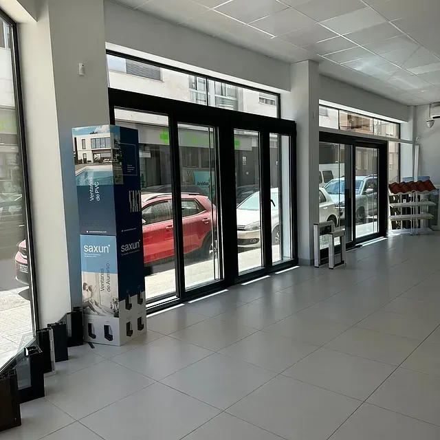 Una habitación grande con muchas ventanas y un coche rojo aparcado al fondo.