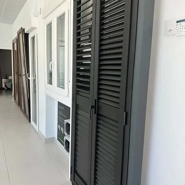 Un pasillo con una hilera de ventanas y contraventanas negras.