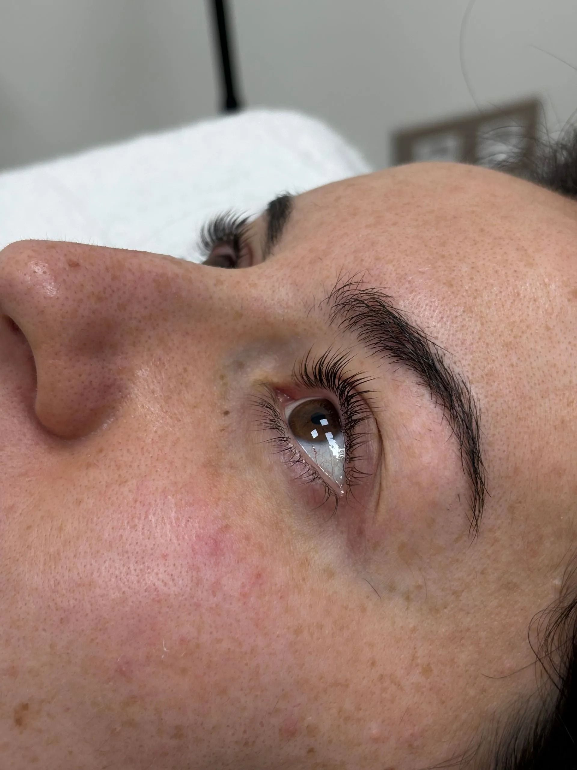 Primer plano del rostro de una persona tumbada en una cama, mirando hacia arriba, con la ceja