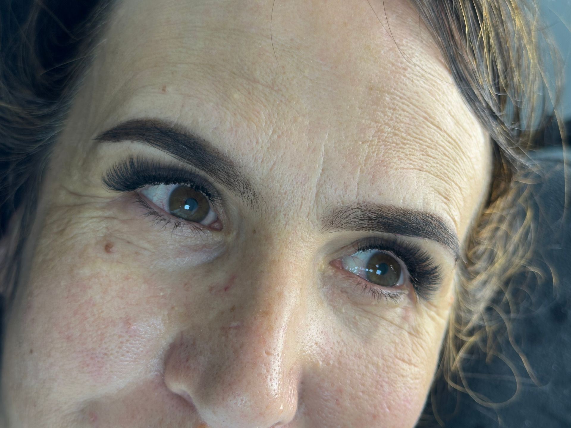 Primer plano del rostro de una mujer con ojos expresivos y cejas oscuras, mirando hacia un lado.