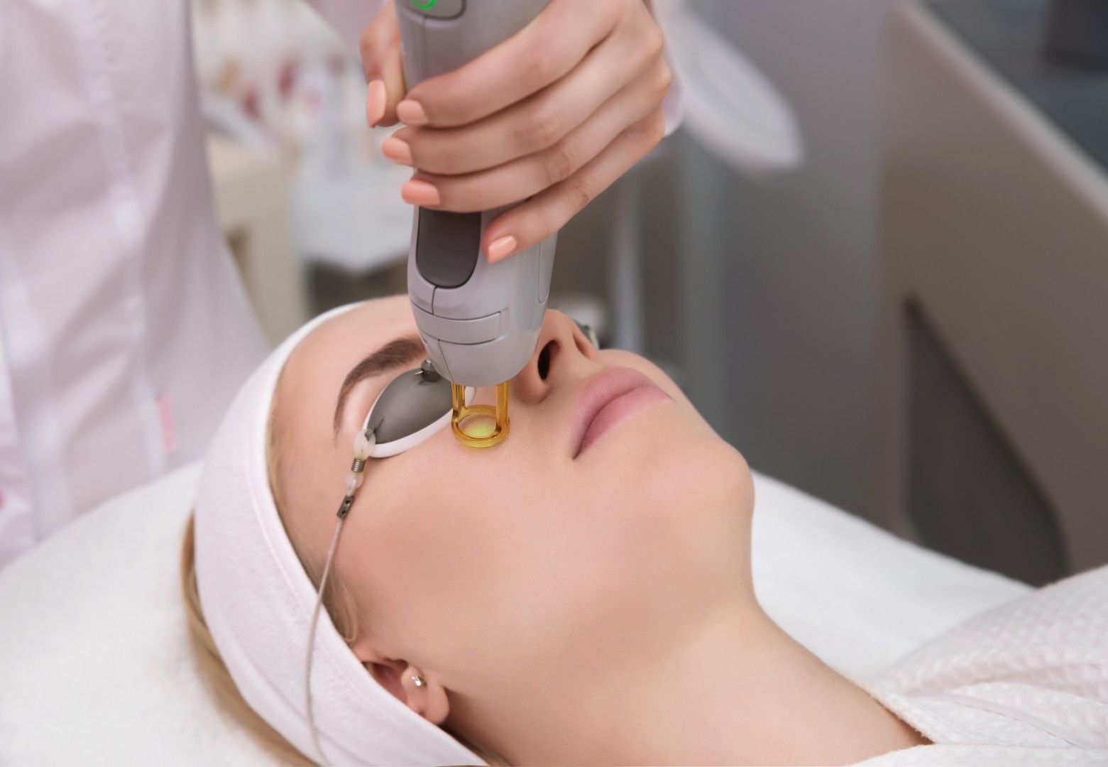 Tratamiento estético con un dispositivo portátil en el rostro de una mujer en un spa