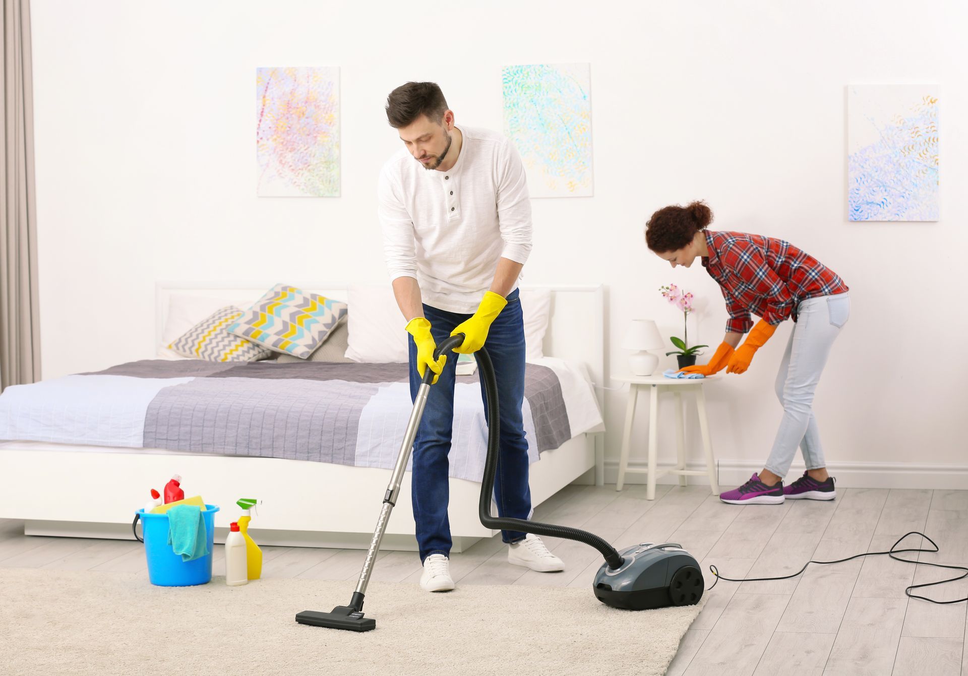 Un couple nettoyant sa chambre à coucher