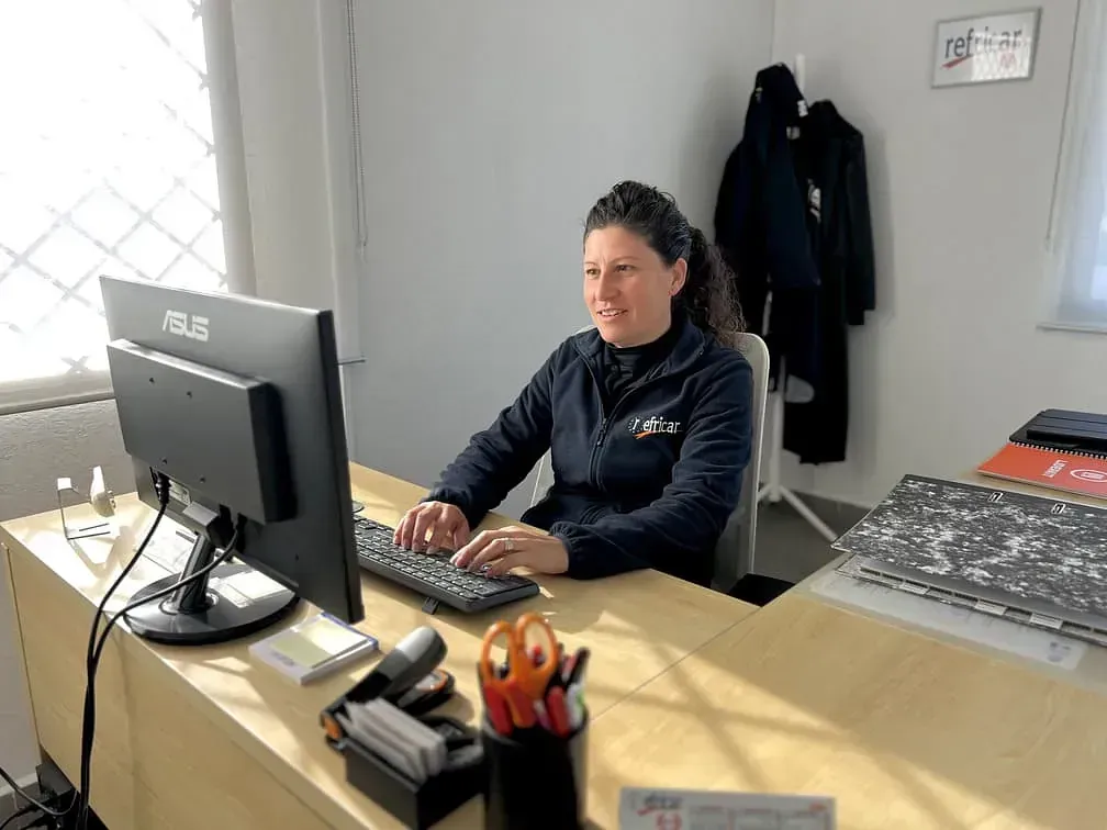 Persona sentada en un escritorio usando una computadora en una oficina luminosa.