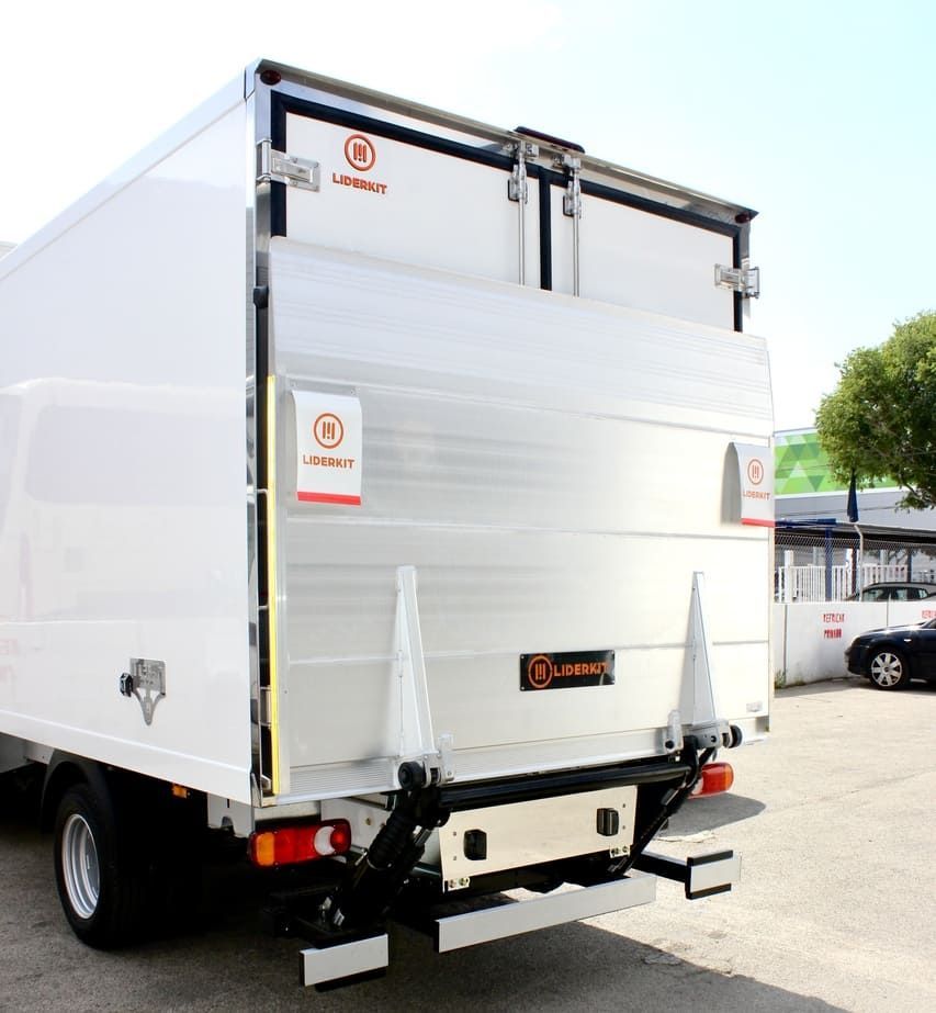 Camión blanco de caja cerrada con plataforma elevadora trasera estacionado al aire libre en un lote