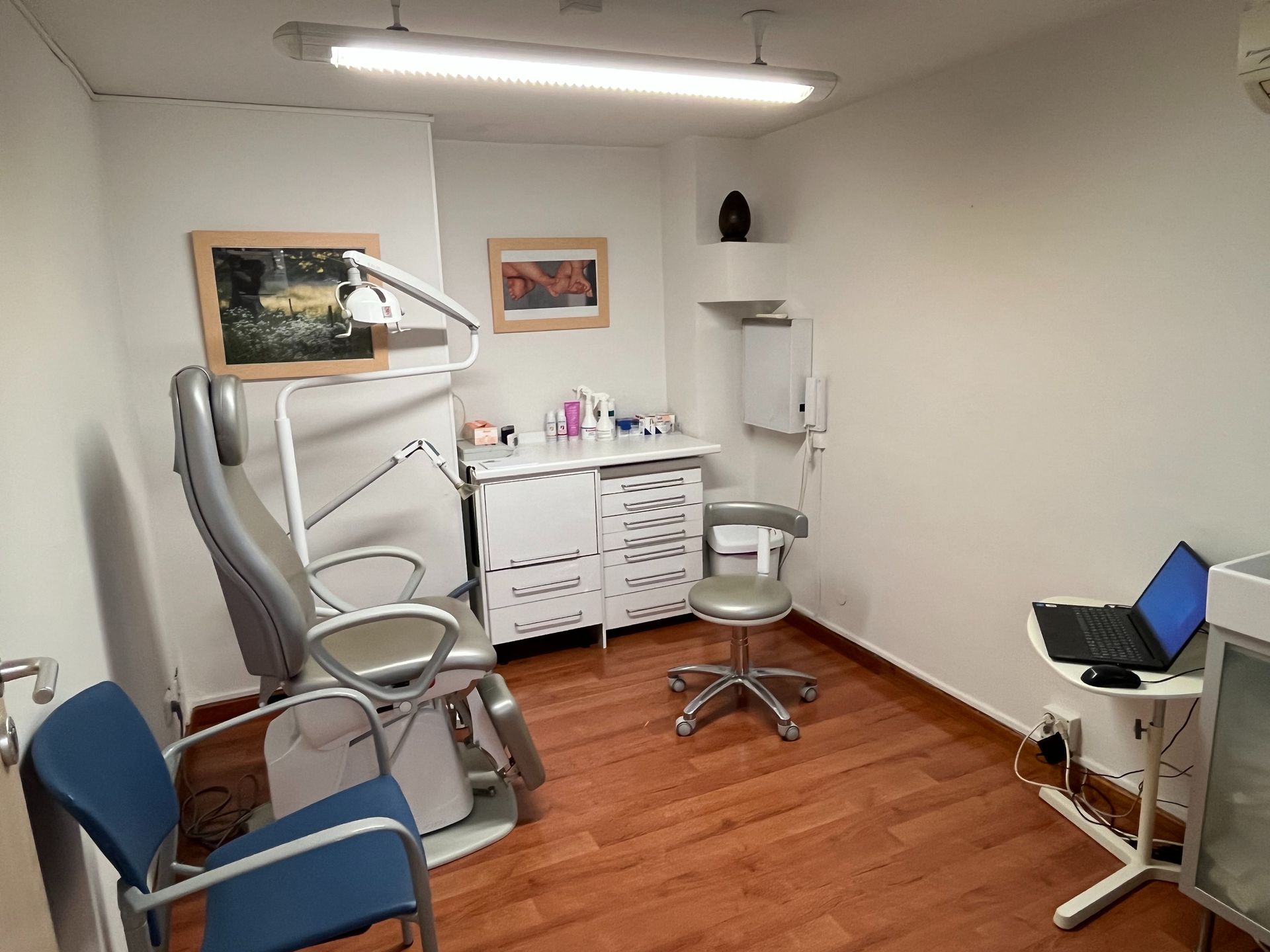 Un consultorio dental con una silla y una computadora portátil en un escritorio.