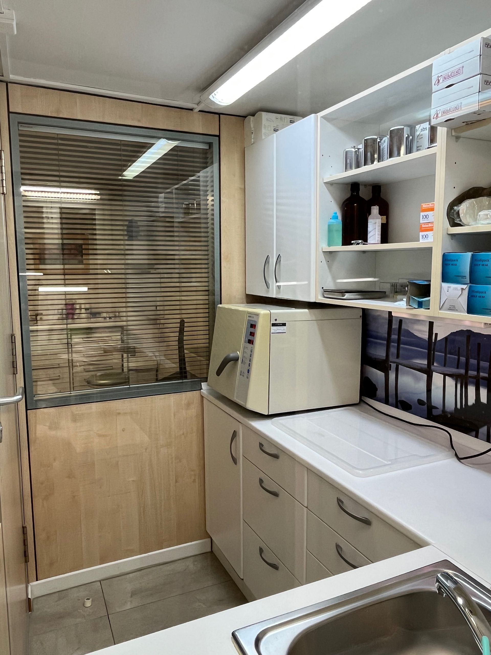 Una cocina con fregadero, armarios, estantes y microondas.