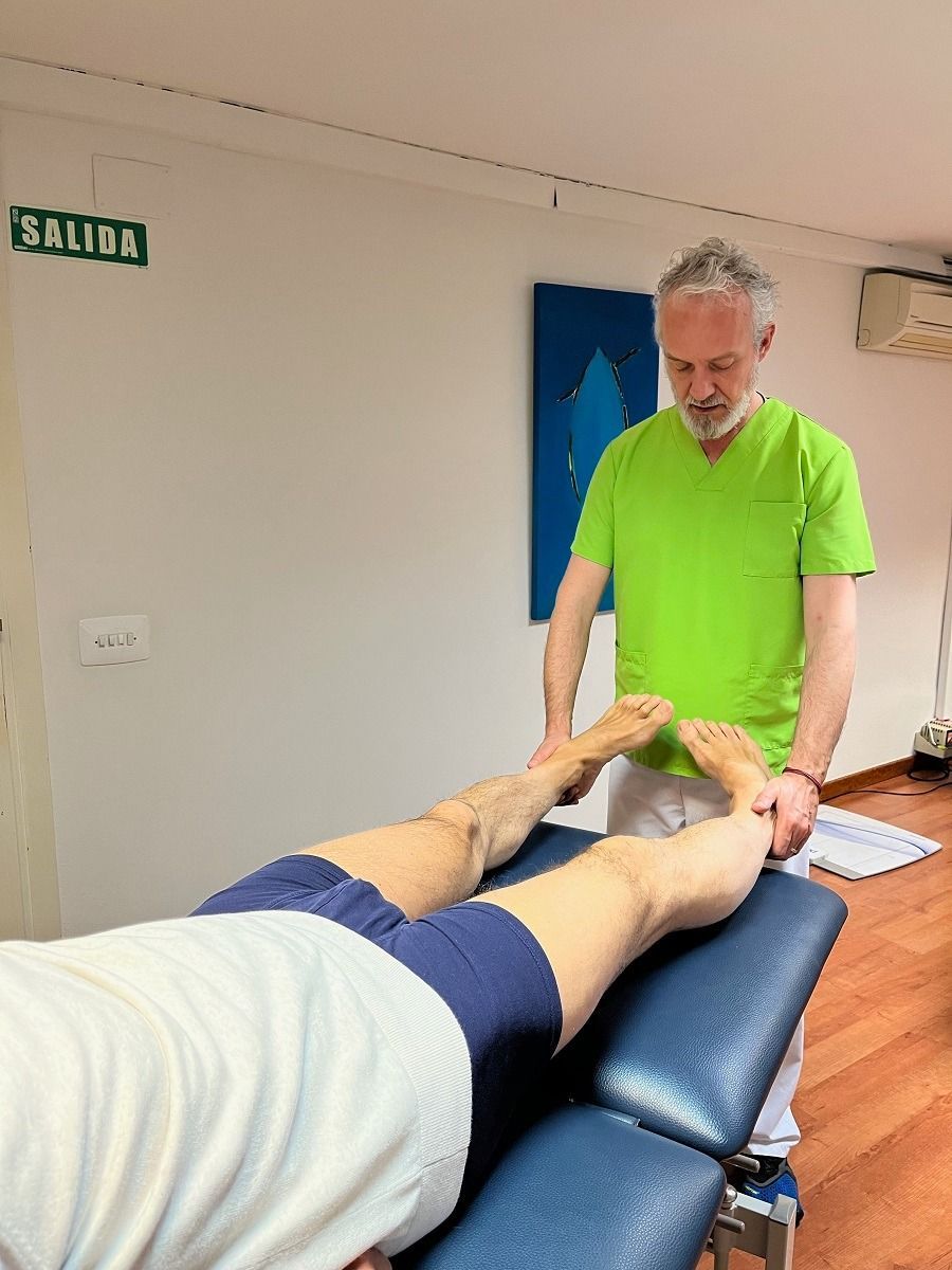 Un hombre con una camisa verde le está dando un masaje de pies a un hombre.