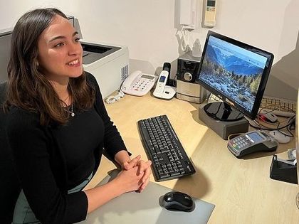 Una mujer está sentada en un escritorio frente a una computadora.