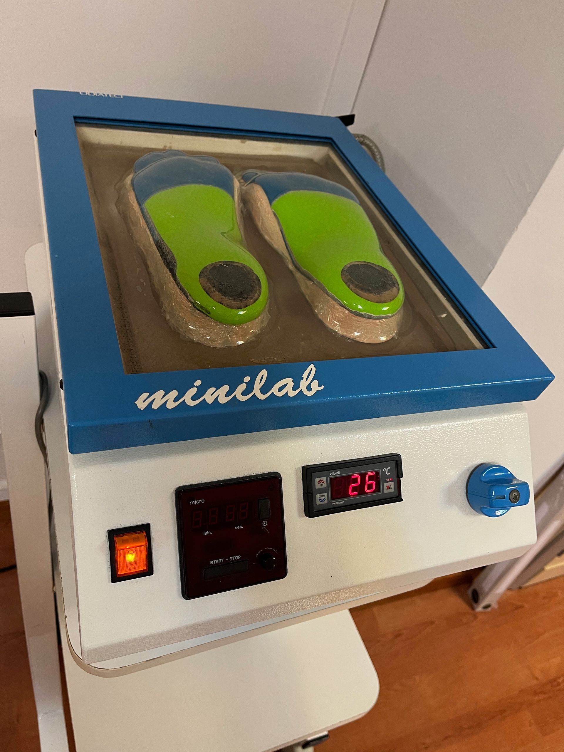 Un par de zapatos verdes están en una máquina que dice minilab