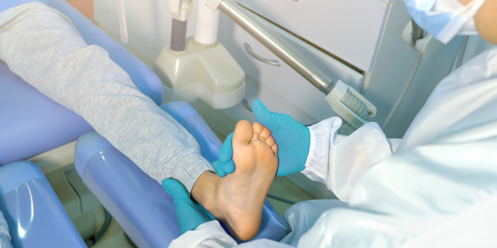 Un dentista está examinando el pie de un niño en una silla dental.
