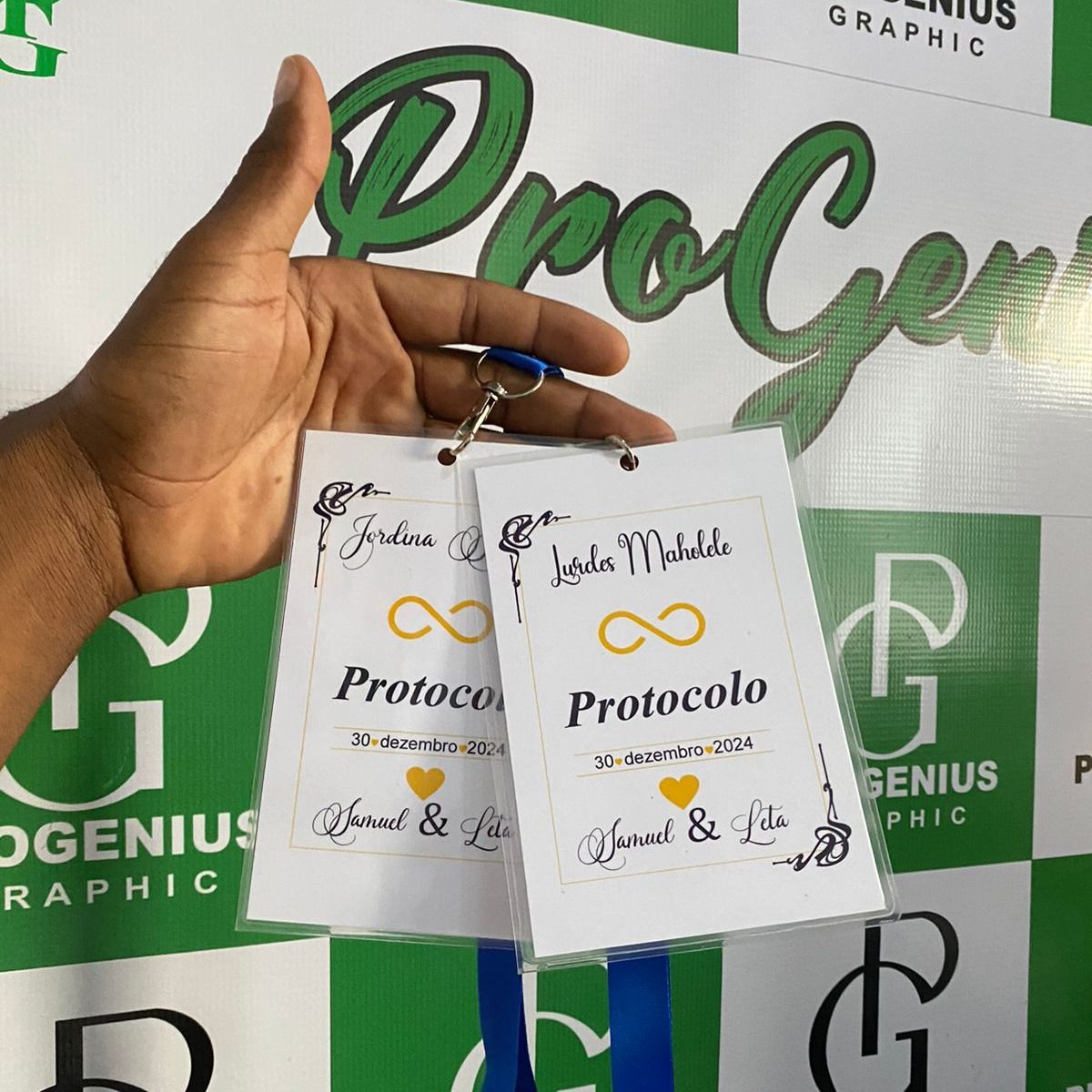 Mão segurando duas etiquetas de presente Protocol brancas com detalhes dourados sobre um fundo verde da Pro Genius Graphic.