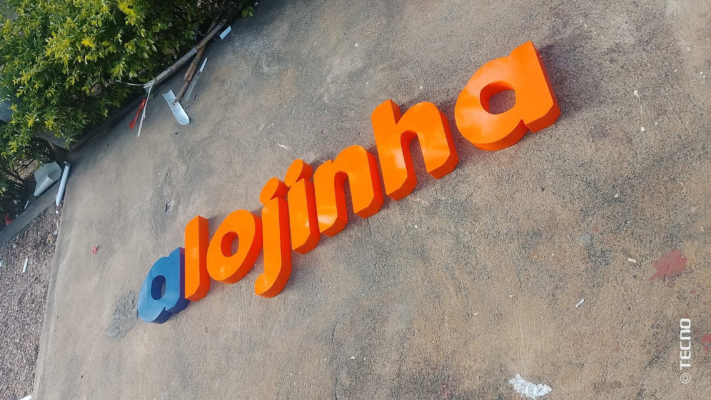 Mão segurando dois abridores de garrafa de chaveiro com pequenos compartimentos para fotos em frente a um veículo vermelho.