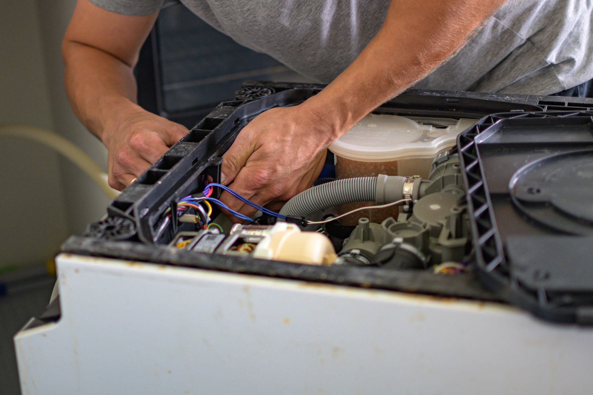 Technicien travaillant à l'intérieur d'un appareil électronique ouvert, avec des fils et des composants.