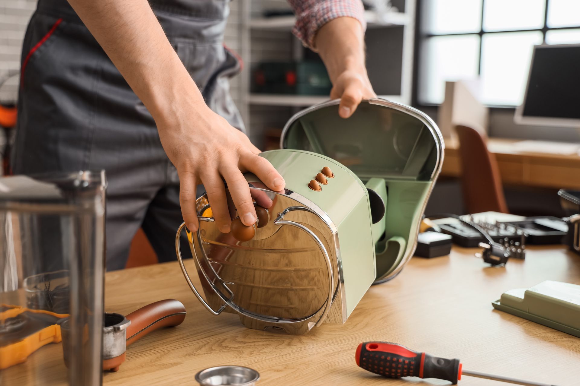 Un homme répare une machine à café sur un établi.