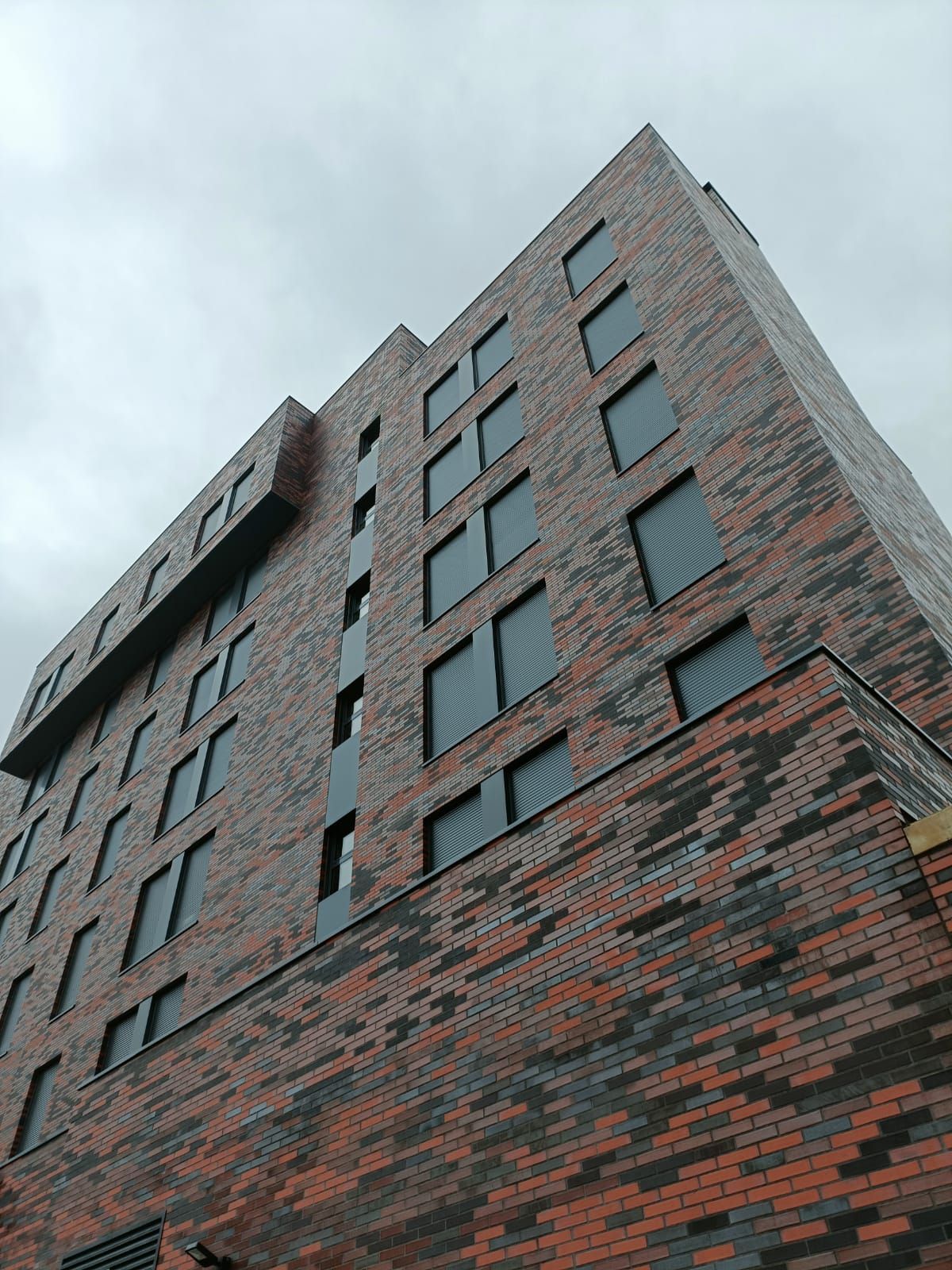 Un edificio alto de ladrillo con muchas ventanas en un día nublado.