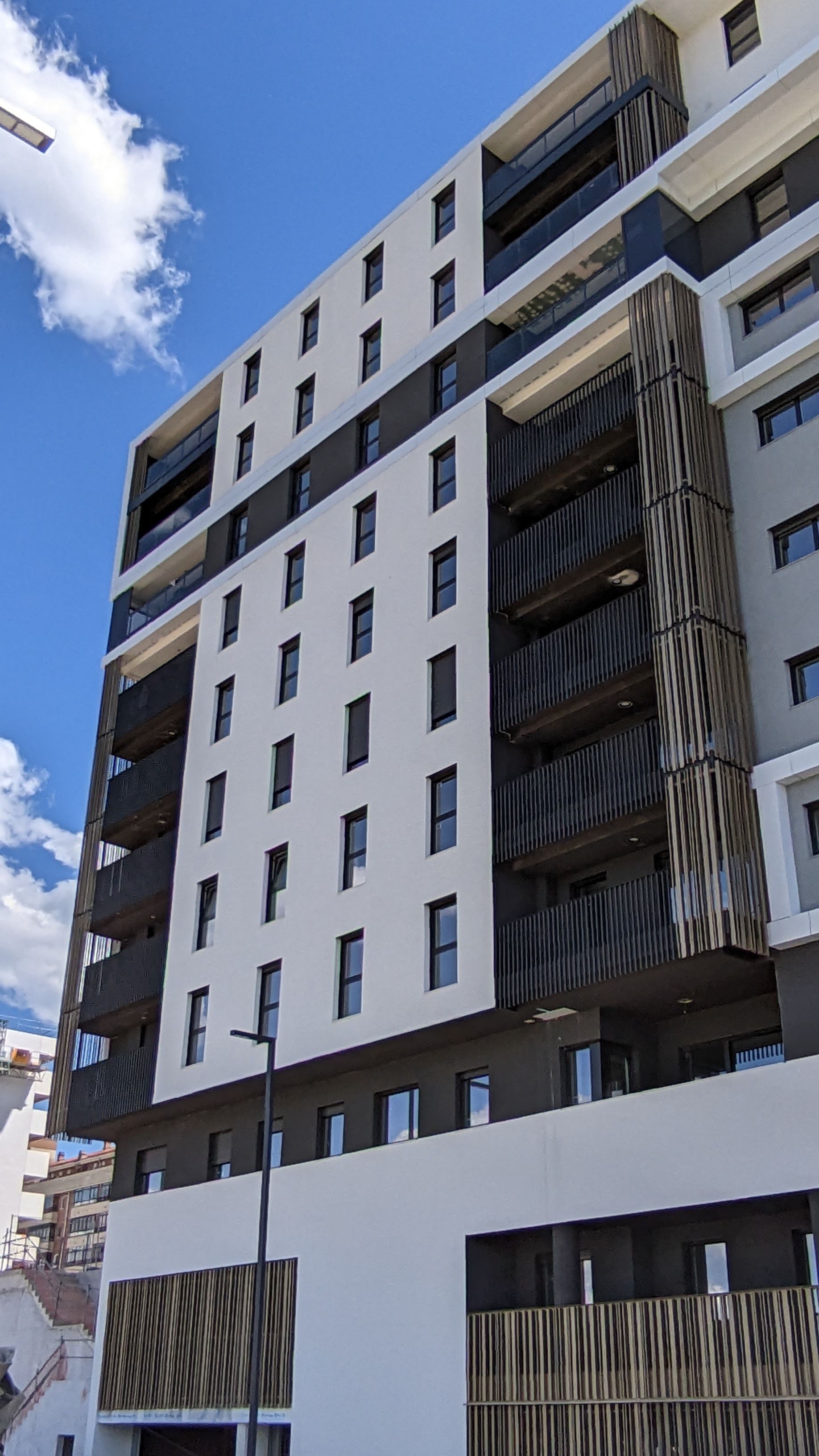 Un edificio alto con muchas ventanas y balcones en un día soleado.