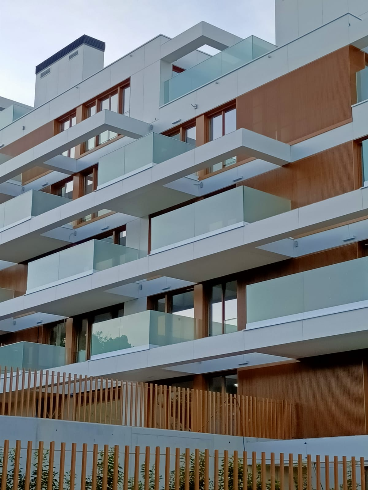 Un edificio grande con muchos balcones y una valla de madera.