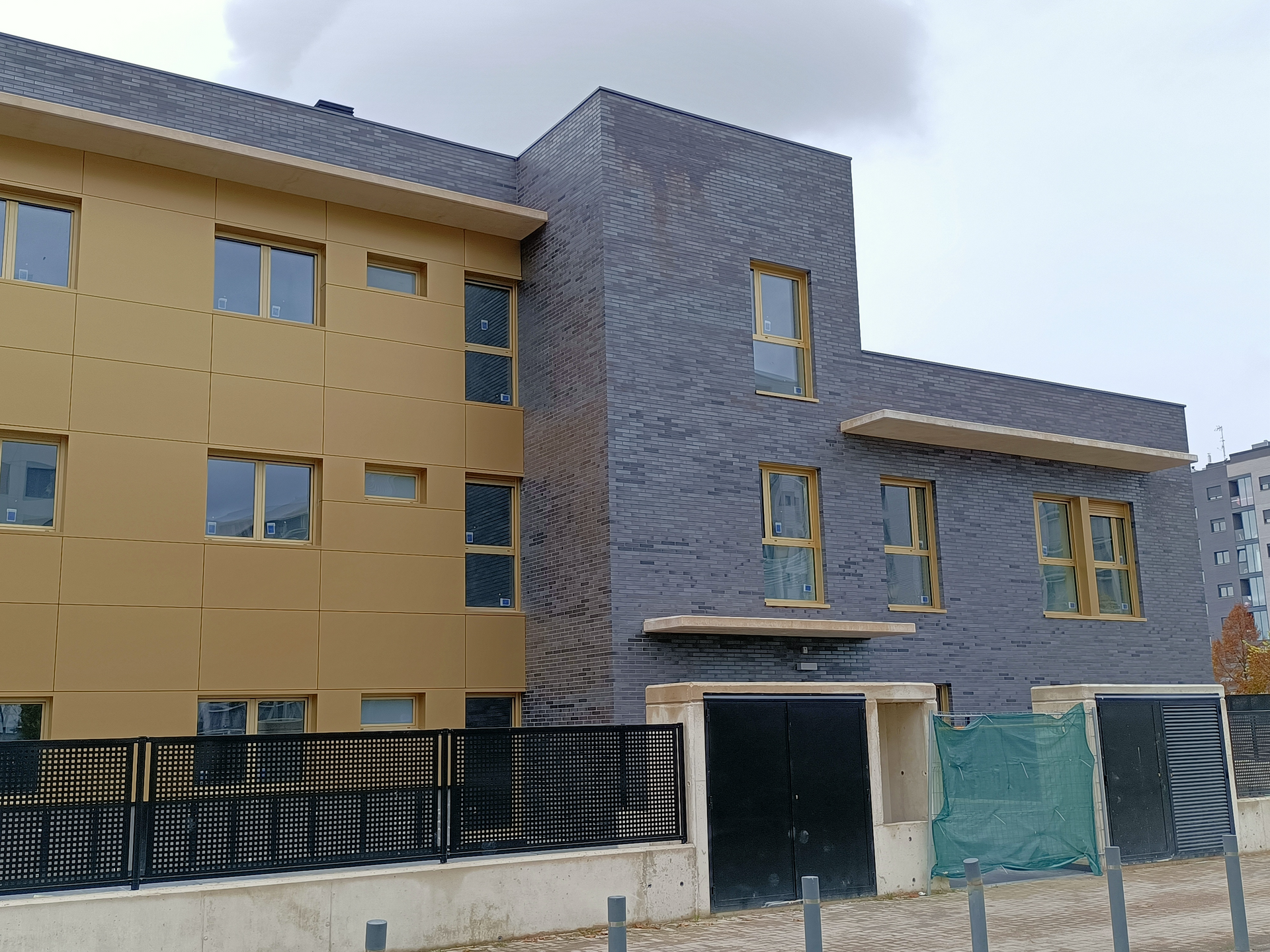 Un edificio grande con muchas ventanas y una valla delante.