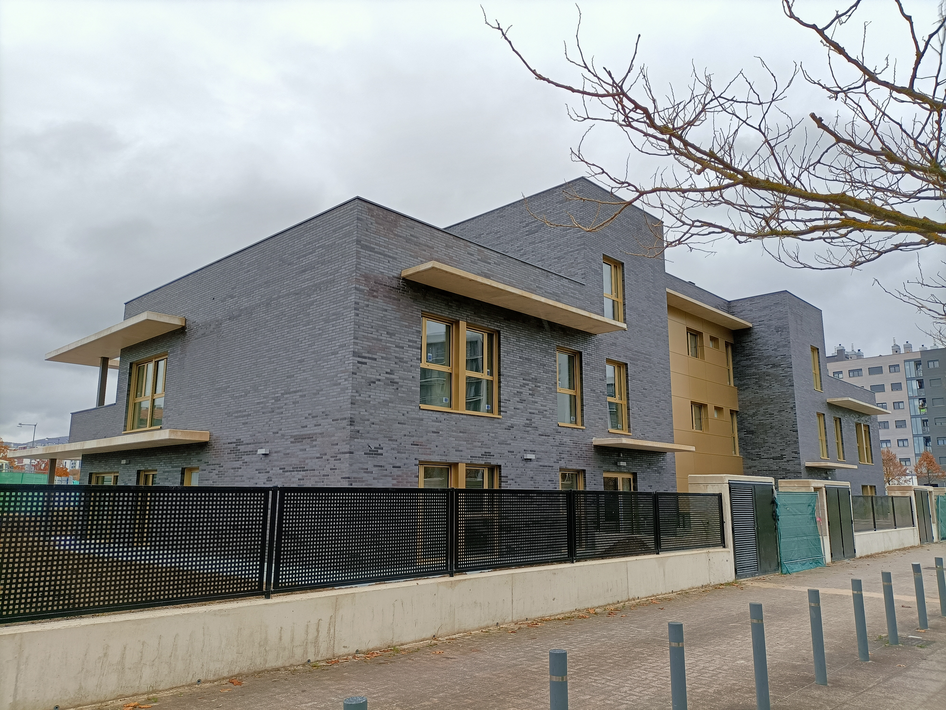 Un edificio grande con una valla a su alrededor y un árbol delante.