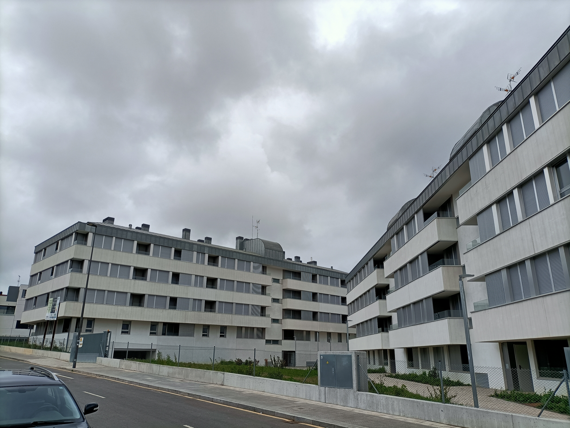 Un coche está aparcado delante de un gran edificio en un día nublado.
