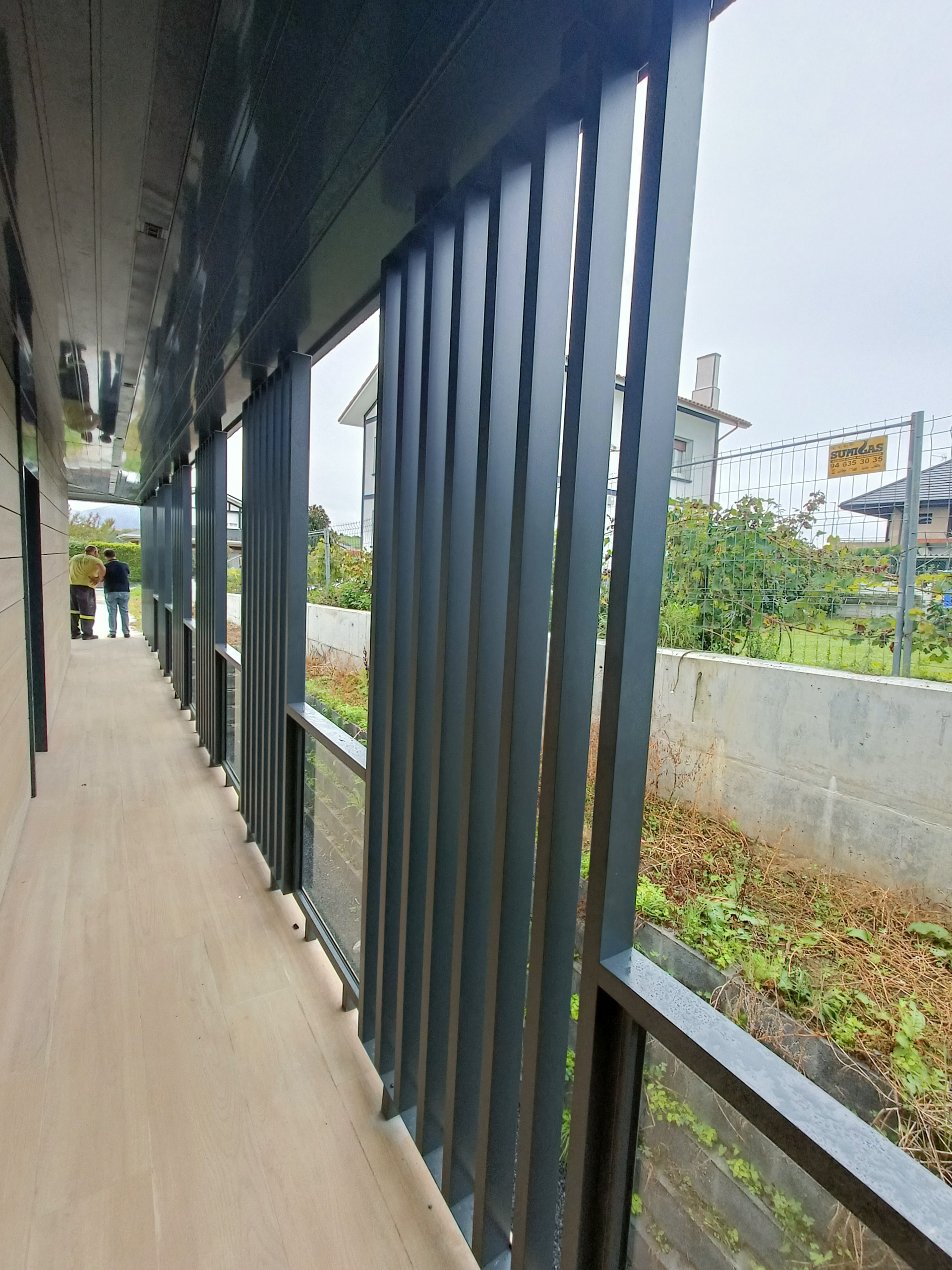 Un pasillo largo con una valla y muchas ventanas.